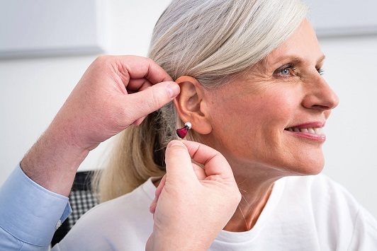 Seniorin bekommt ein modernes Hörgerät vom Hörakustiker zur Hörverbesserung angepasst.